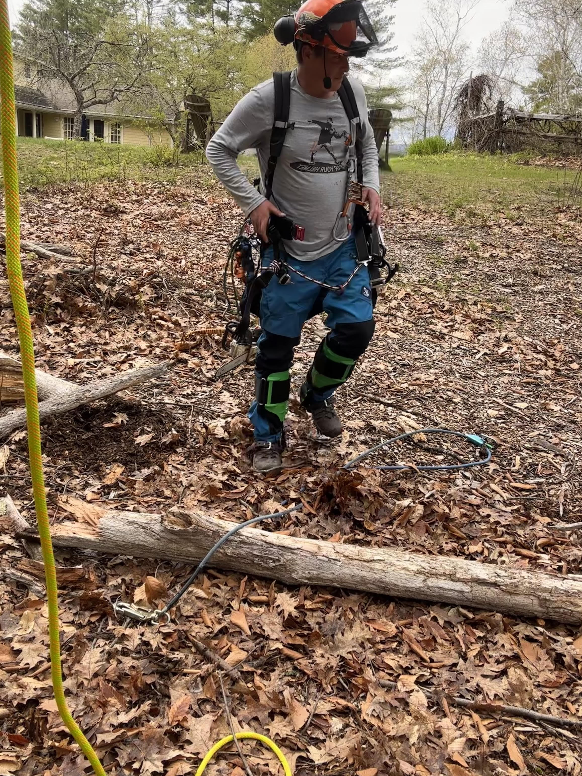 A man standing in a leaf covered field next to a tree